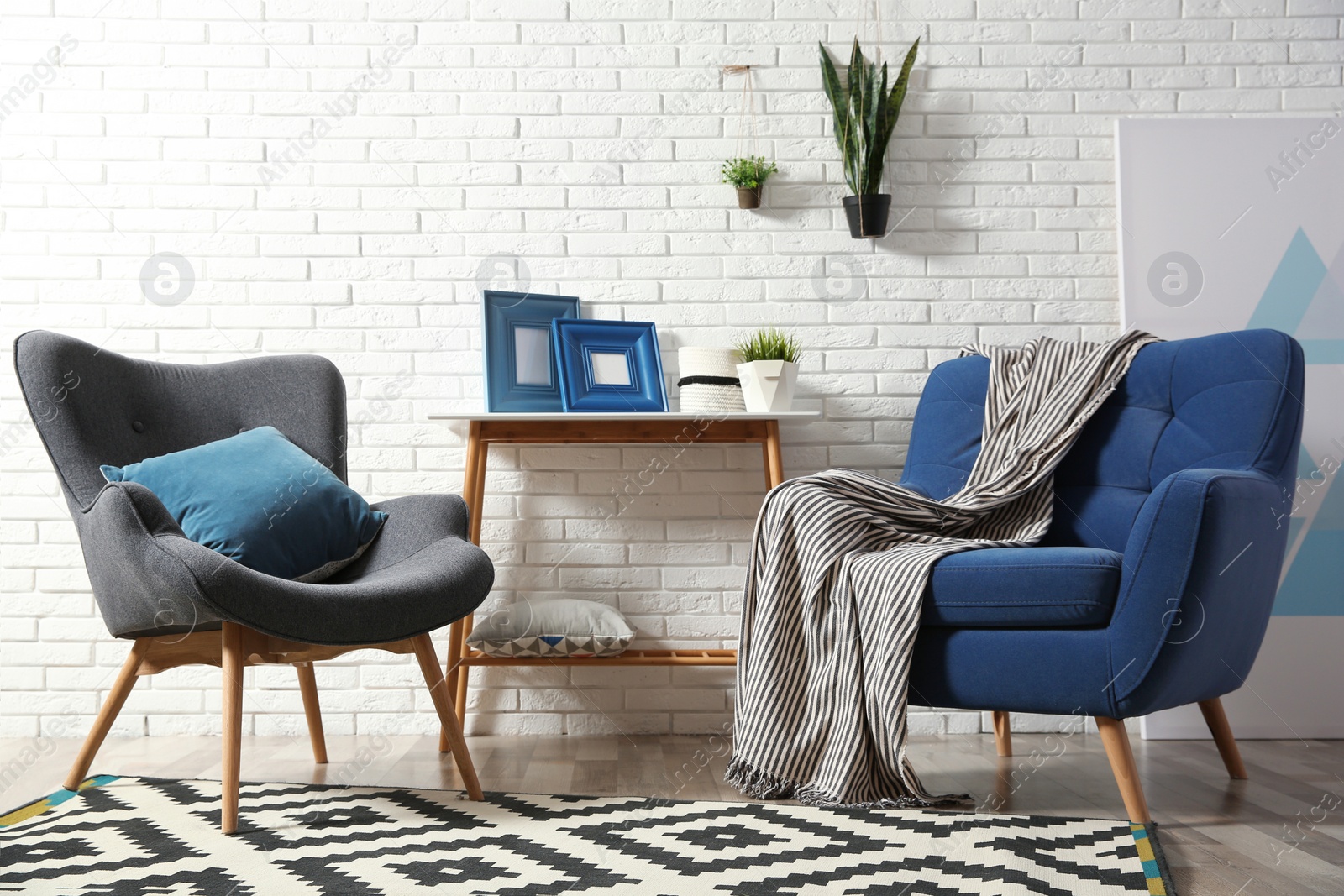 Photo of Modern interior with cozy armchairs and table near brick wall