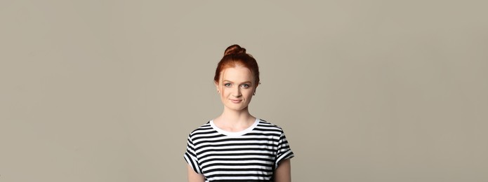 Image of Candid portrait of happy red haired woman with charming smile on beige background. Horizontal banner design