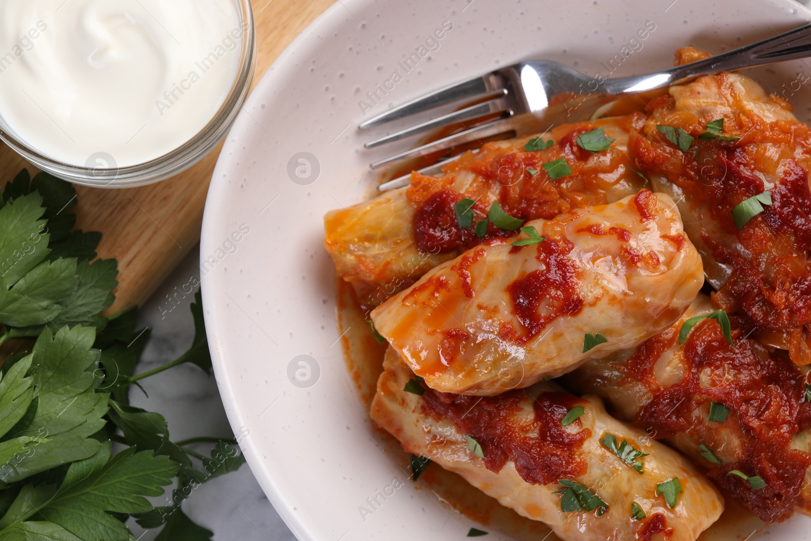 Photo of Delicious stuffed cabbage rolls cooked with homemade tomato sauce on table, flat lay