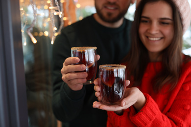 Photo of Lovely couple with tasty mulled wine outdoors, focus on hands
