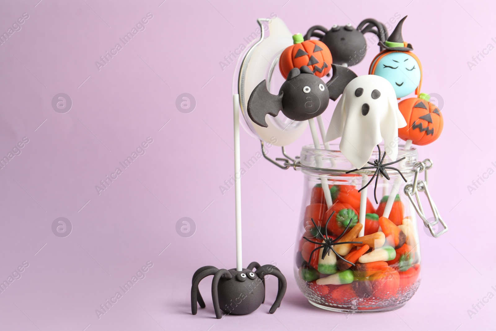 Photo of Delicious Halloween themed cake pops on pink background, space for text