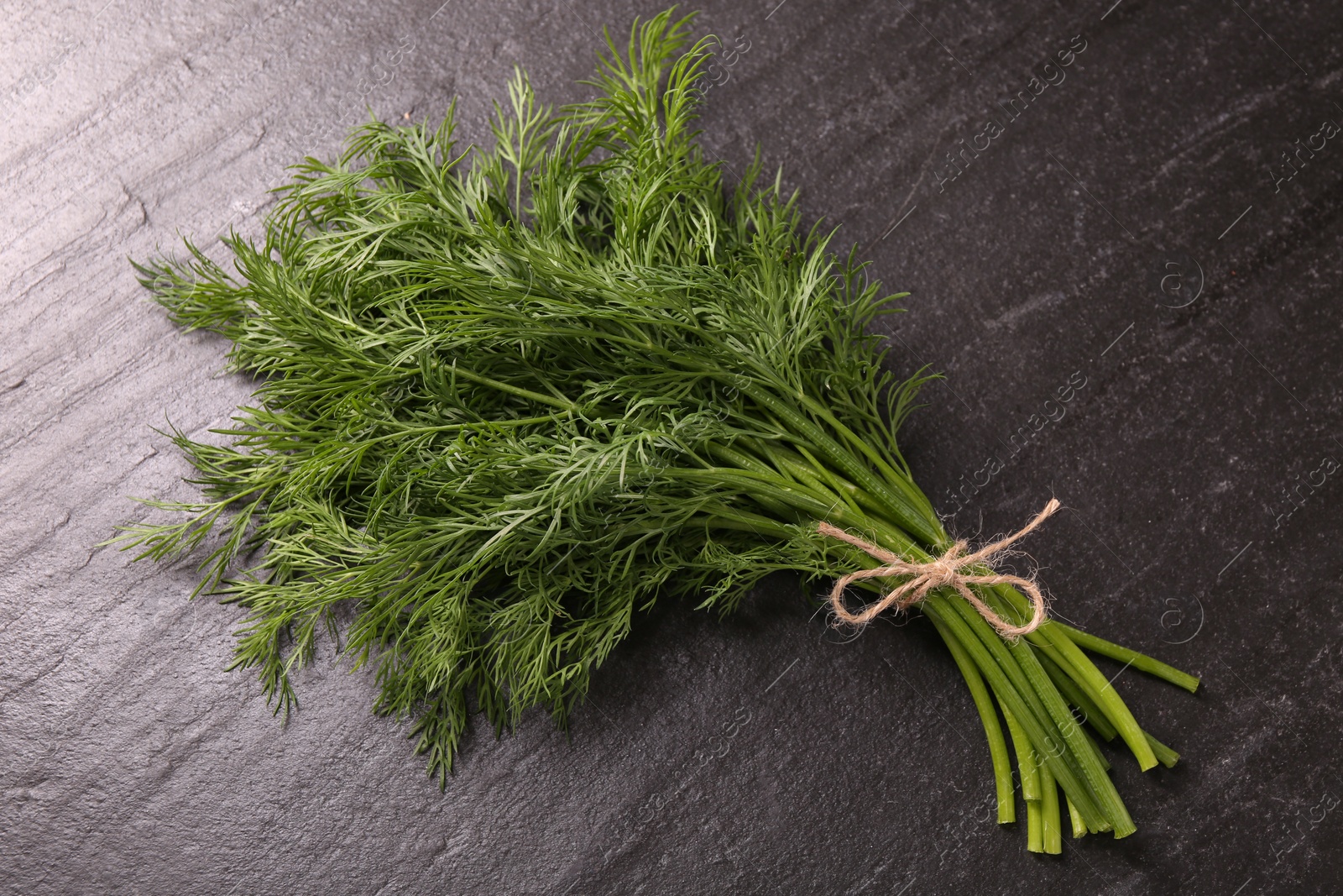 Photo of Bunch of fresh dill on dark textured table, top view