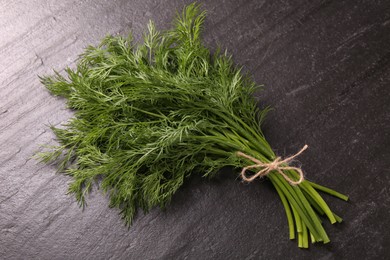 Bunch of fresh dill on dark textured table, top view