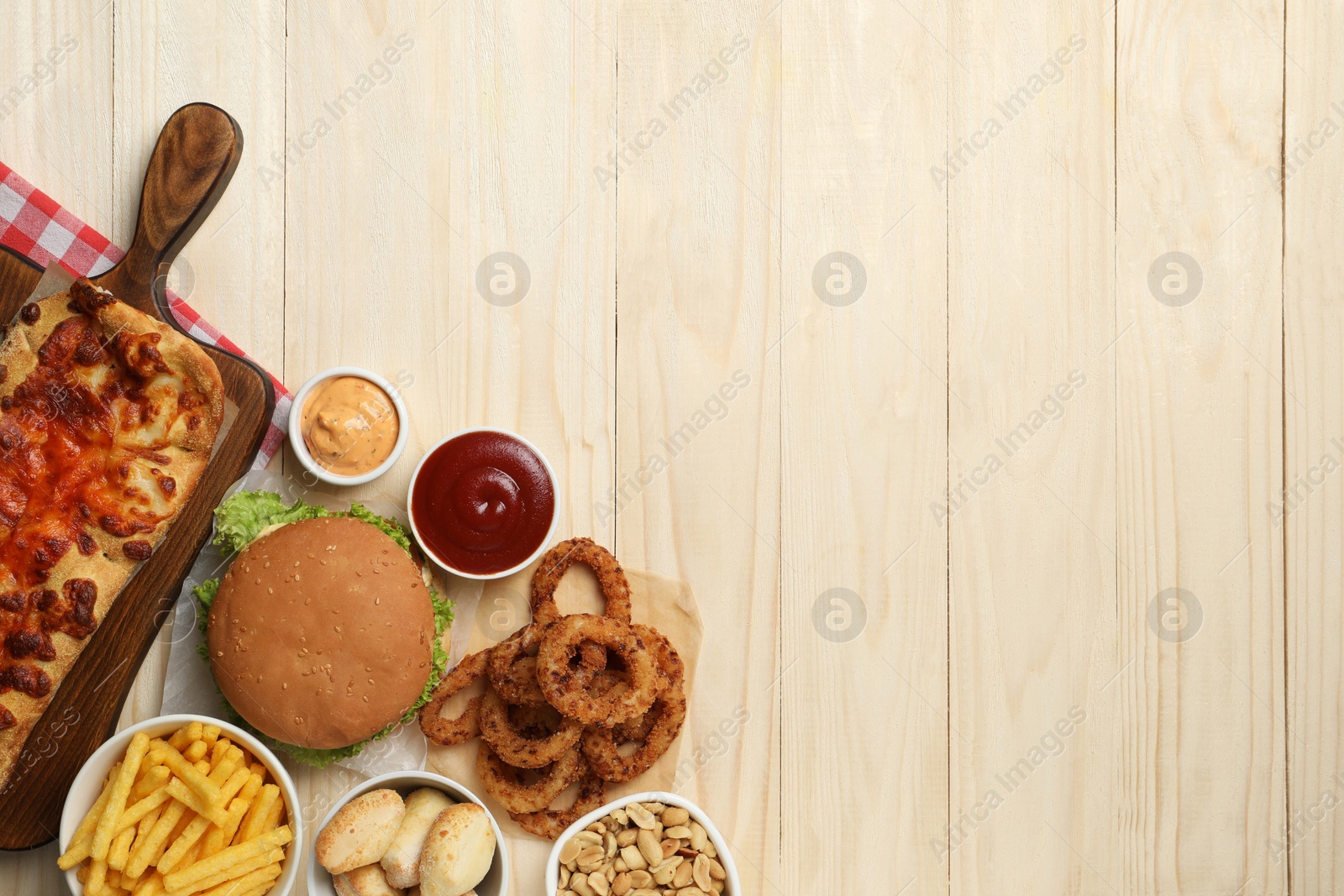 Photo of French fries, burger and other fast food on wooden table, flat lay with space for text