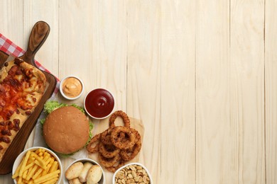 French fries, burger and other fast food on wooden table, flat lay with space for text