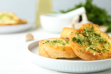 Photo of Slices of toasted bread with garlic and herbs on white wooden table, closeup