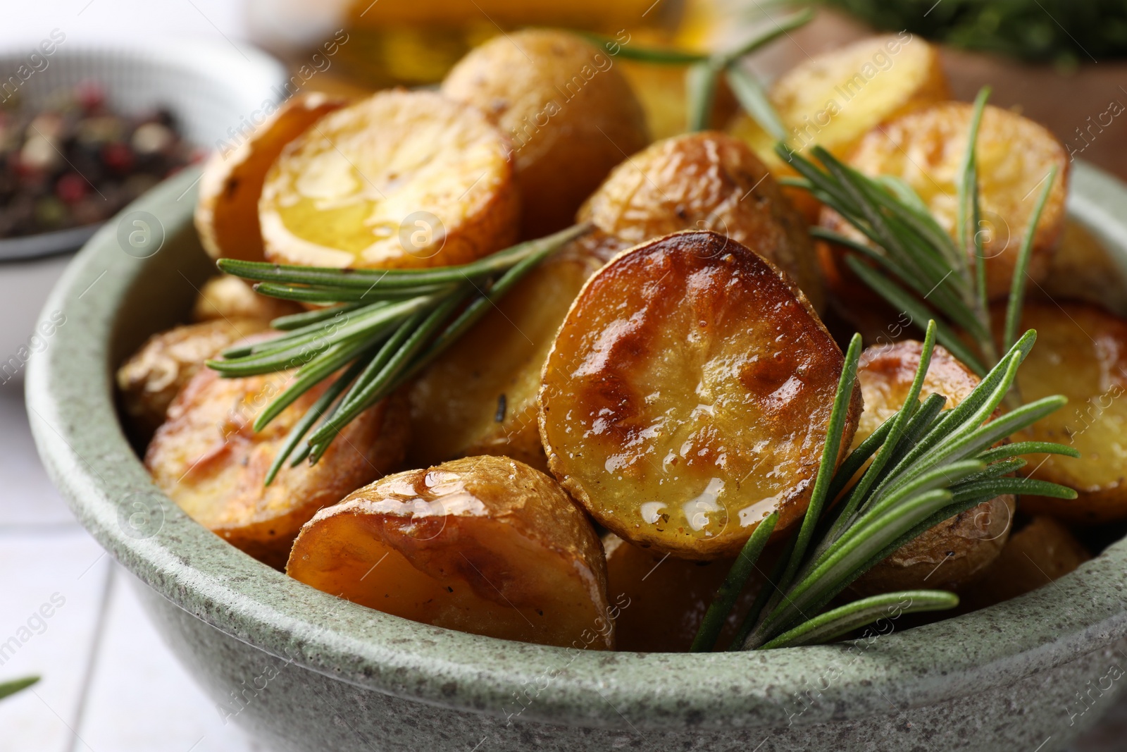 Tasty baked potato and aromatic rosemary in bowl on table, closeup Photo of Tasty baked potato and aromatic rosemary in bowl on table, closeup