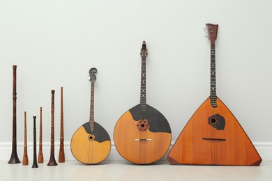 Set of different wooden musical instruments near white wall indoors