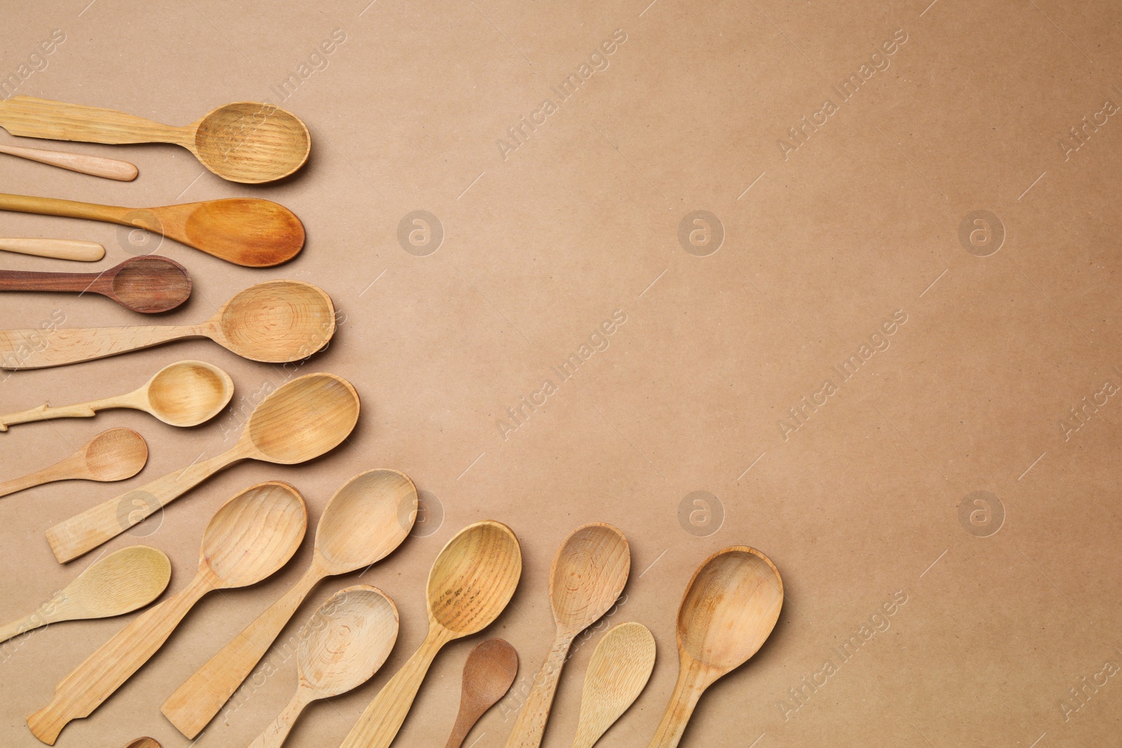 Photo of New wooden spoons on brown background, flat lay with space for text. Cooking utensils