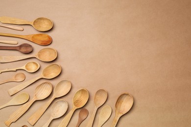 New wooden spoons on brown background, flat lay with space for text. Cooking utensils