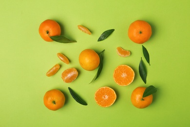 Photo of Composition with tangerines and leaves on color background, flat lay