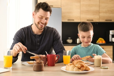 Dad and son having breakfast together in kitchen