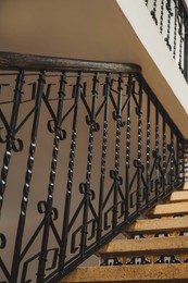 Photo of Stairs and black metal railing indoors, low angle view. Interior design