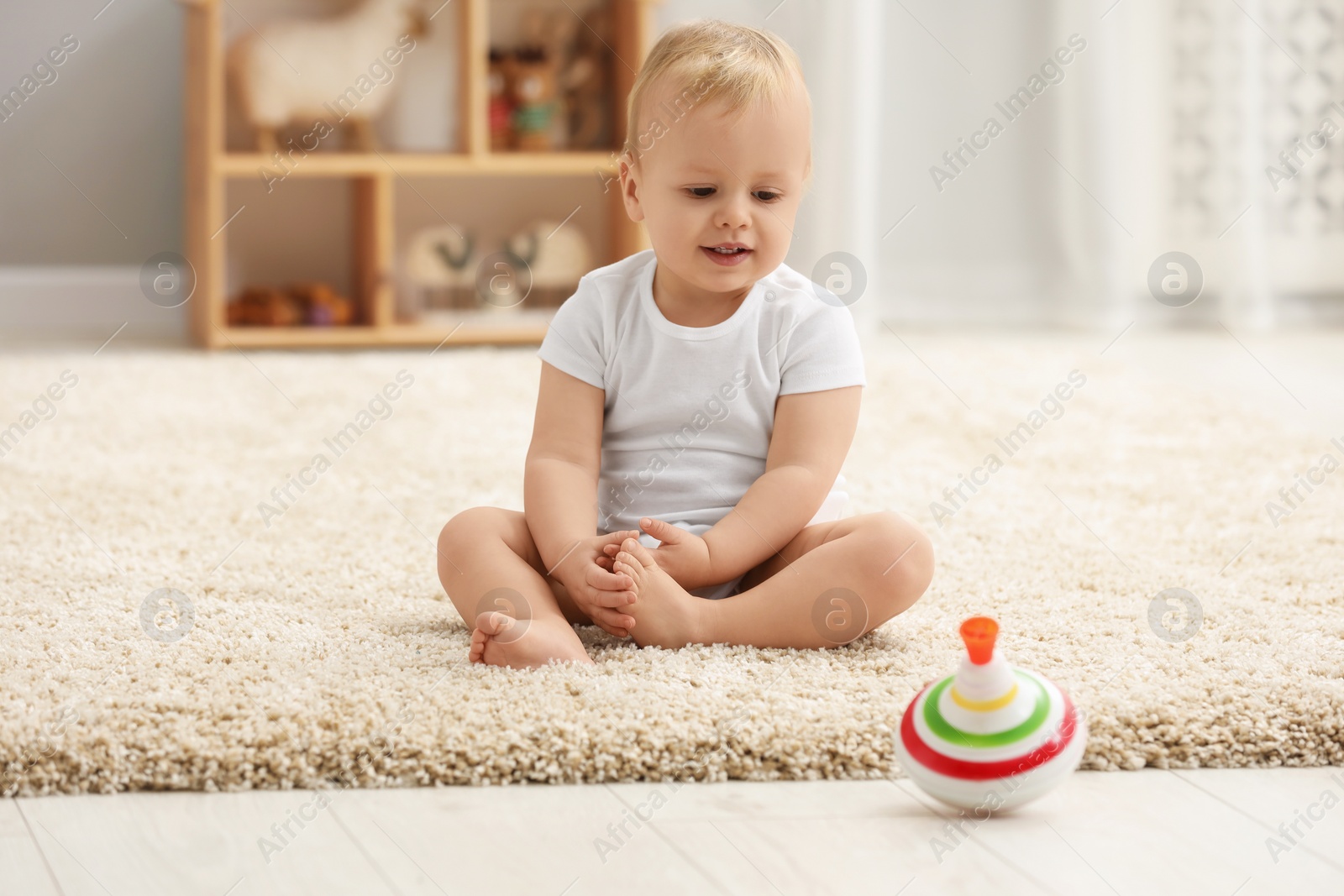 Photo of Children toys. Cute little boy and spinning top on rug at home