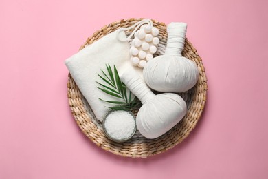 Photo of Beautiful spa composition with herbal massage bags and different care products on pink background, flat lay