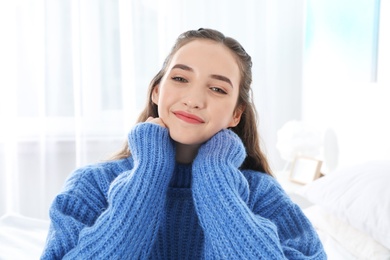 Photo of Beautiful teenage girl in warm cozy sweater at home