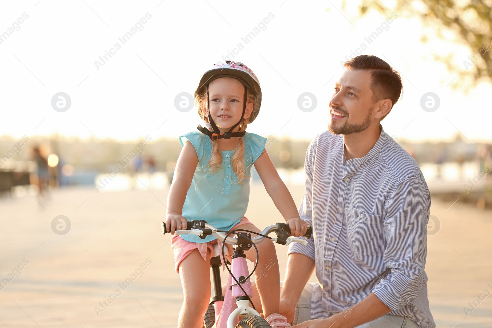 Photo of Father teaching daughter to ride bicycle on street