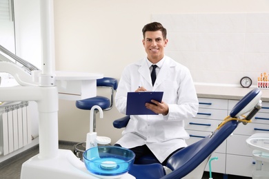 Photo of Portrait of professional male dentist with clipboard in clinic