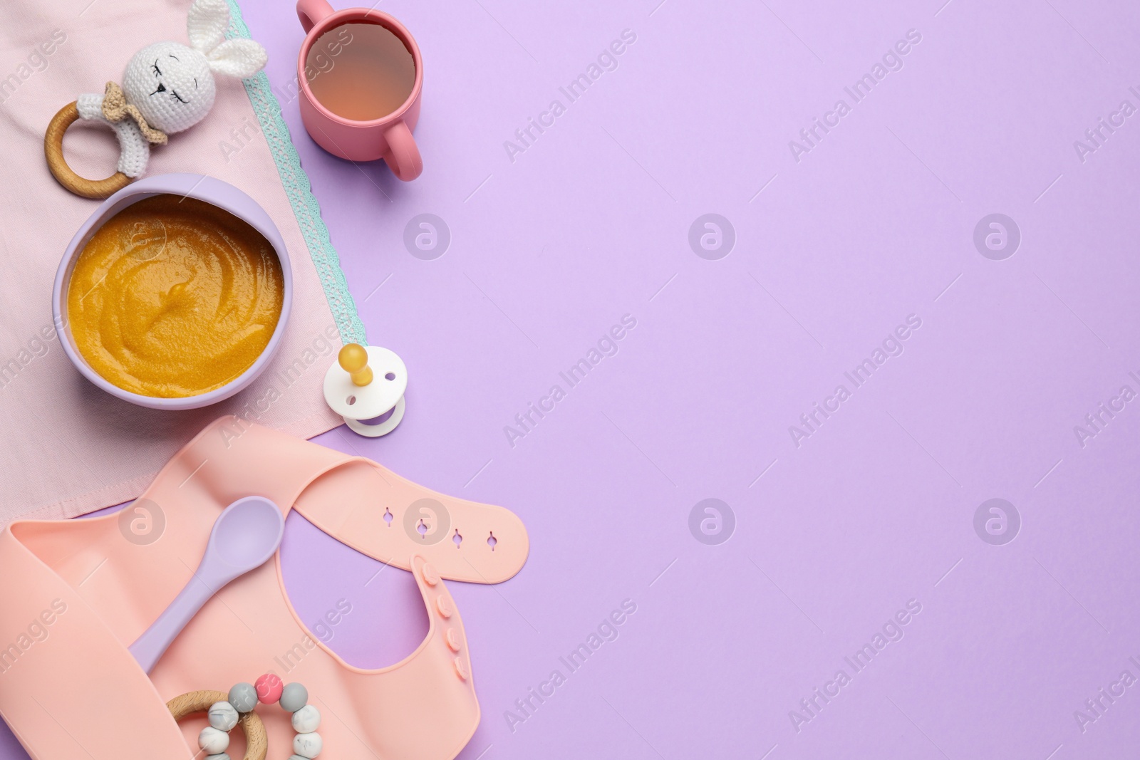 Photo of Healthy baby food in bowl and accessories on violet background, flat lay. Space for text