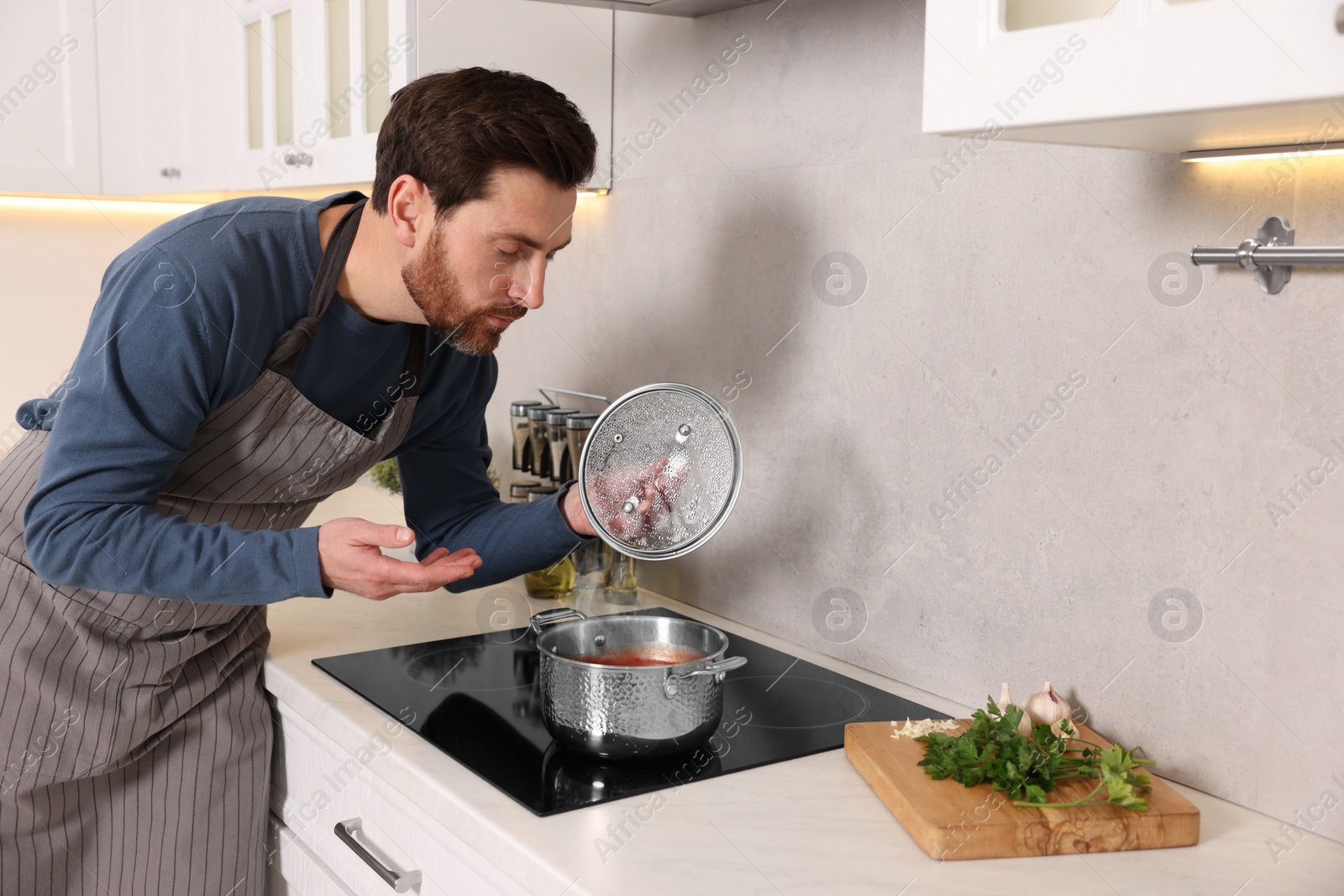 Photo of Man cooking delicious tomato soup in kitchen