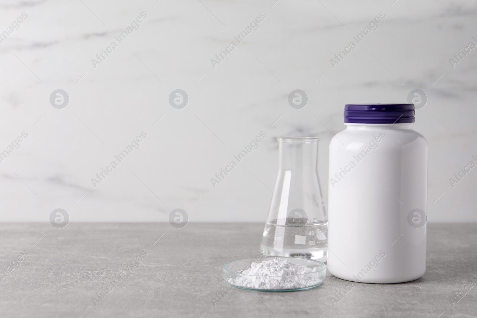 Photo of Petri dish with calcium carbonate powder, jar and laboratory flask on light grey table. Space for text