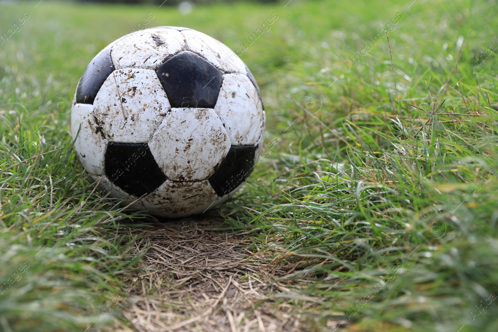 Photo of Dirty soccer ball on green grass outdoors, space for text