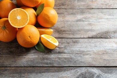 Fresh oranges with leaves on wooden background, top view. Space for text