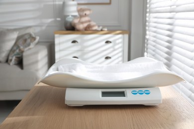 Photo of Modern digital baby scales on wooden table in room