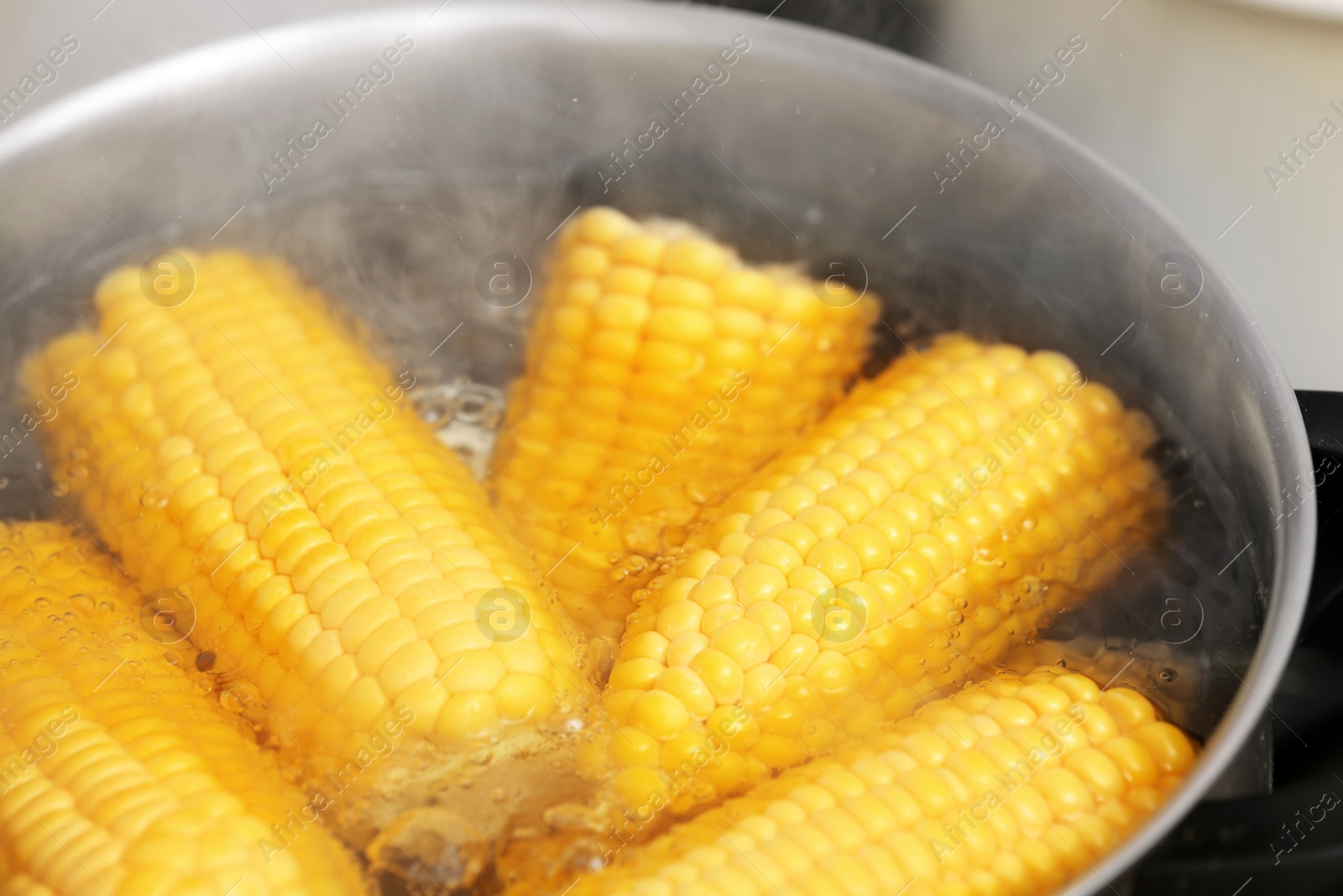 Photo of Stewpot with boiling water and corn cobs, closeup