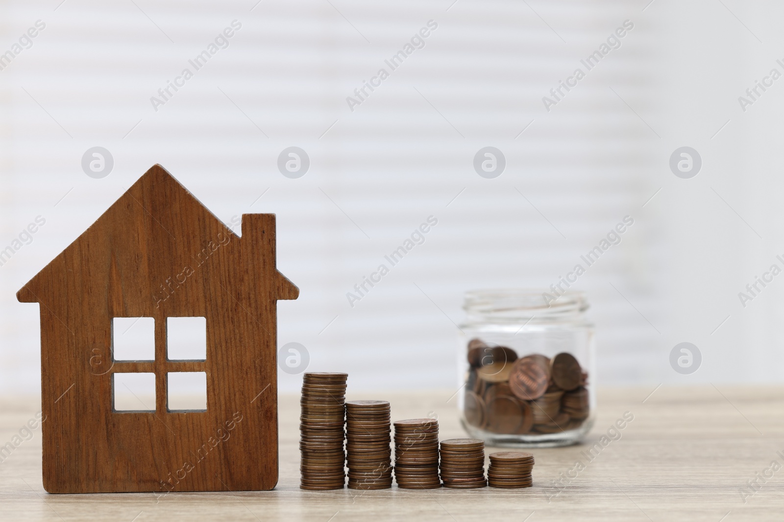 Photo of House model and stacked coins on wooden table