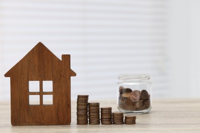 House model and stacked coins on wooden table