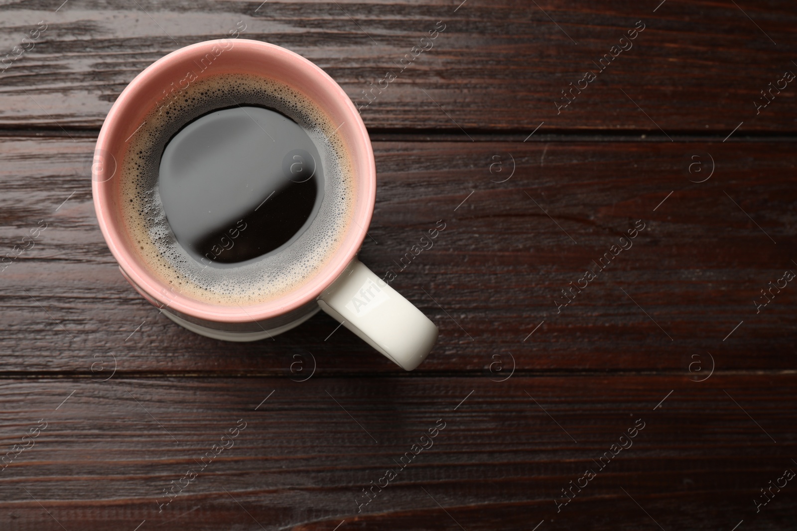 Photo of Cup of aromatic coffee on wooden table, top view. Space for text