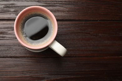 Photo of Cup of aromatic coffee on wooden table, top view. Space for text