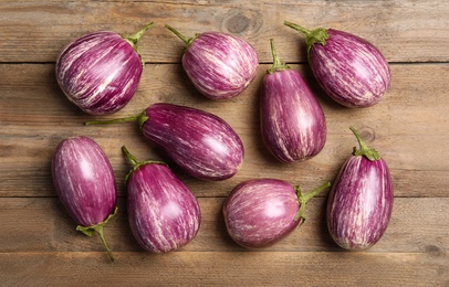 Photo of Raw ripe eggplants on wooden table, flat lay