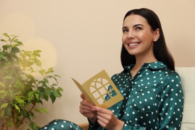 Happy woman holding greeting card in living room