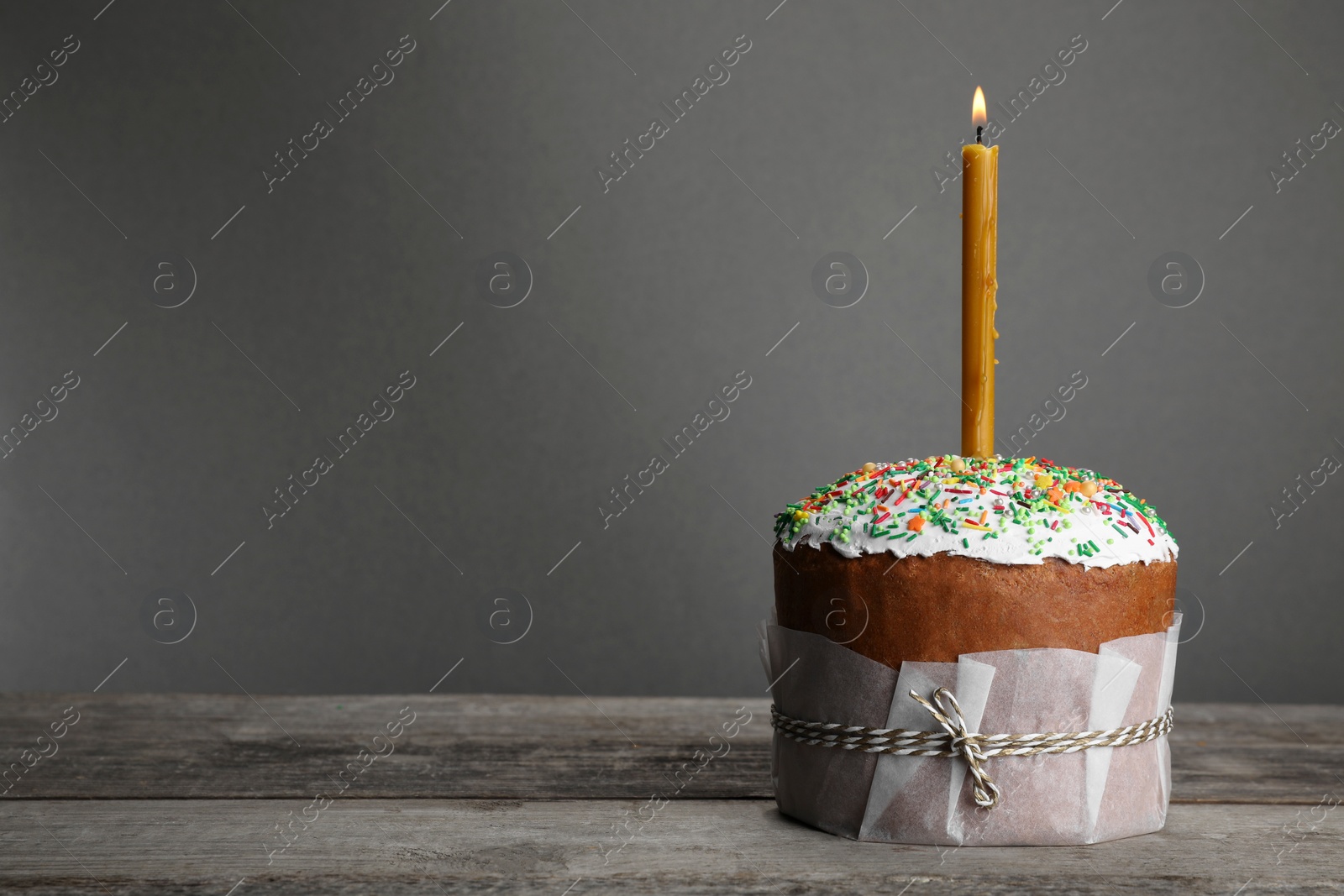 Photo of Traditional Easter cake with sprinkles and burning candle, space for text