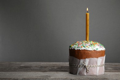 Photo of Traditional Easter cake with sprinkles and burning candle, space for text