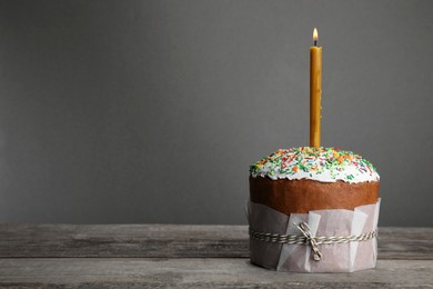 Traditional Easter cake with sprinkles and burning candle, space for text