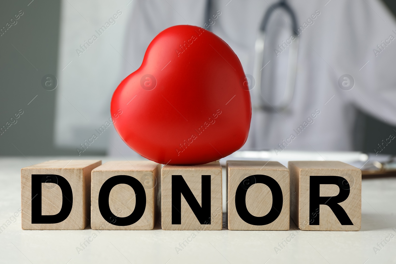 Photo of Wooden cubes with word Donor and small red heart on white table