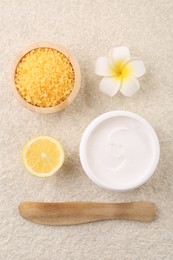 Flat lay composition with moisturizing cream in open jar and other body care products on light textured table