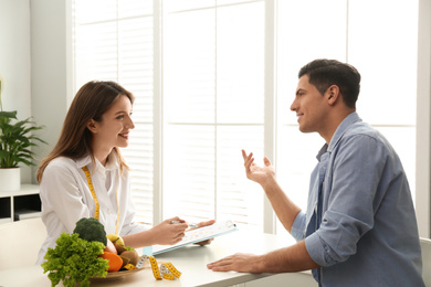 Photo of Young nutritionist consulting patient at table in clinic