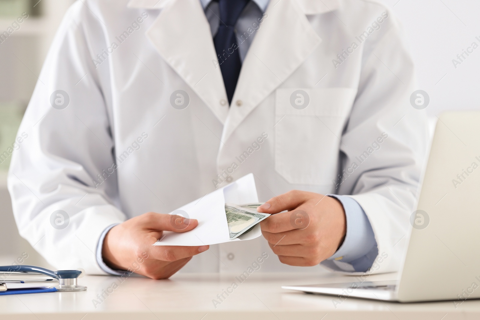 Photo of Doctor with bribe at desk in clinic, closeup. Corrupted medicine