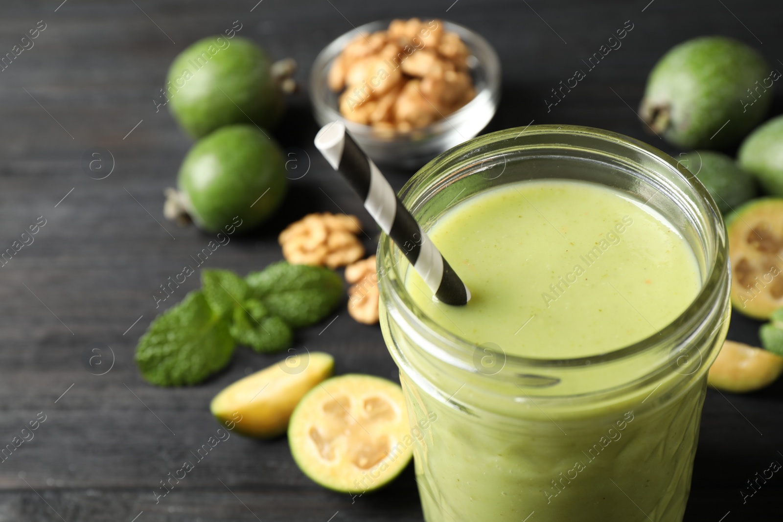 Photo of Fresh feijoa smoothie in glass on black wooden table, closeup