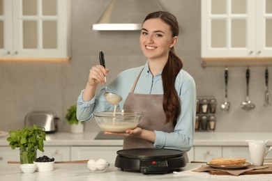 Photo of Happy woman with dough for crepes at white marble table in kitchen