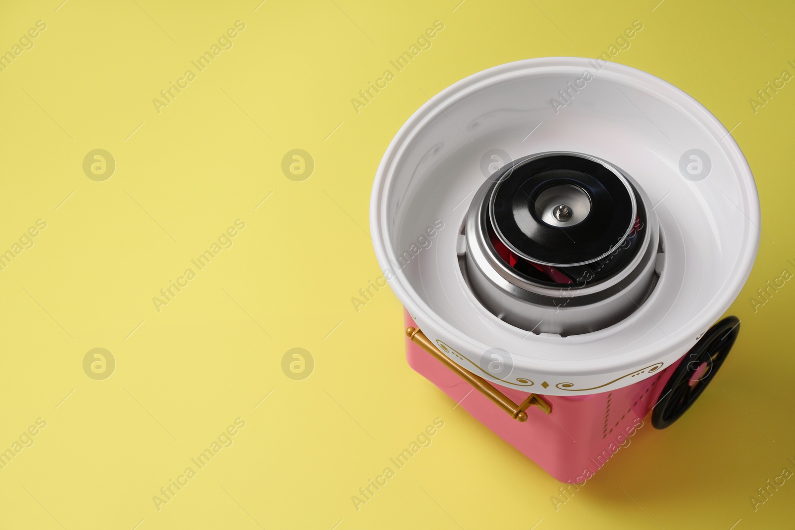 Photo of Portable candy cotton machine on yellow background, above view. Space for text