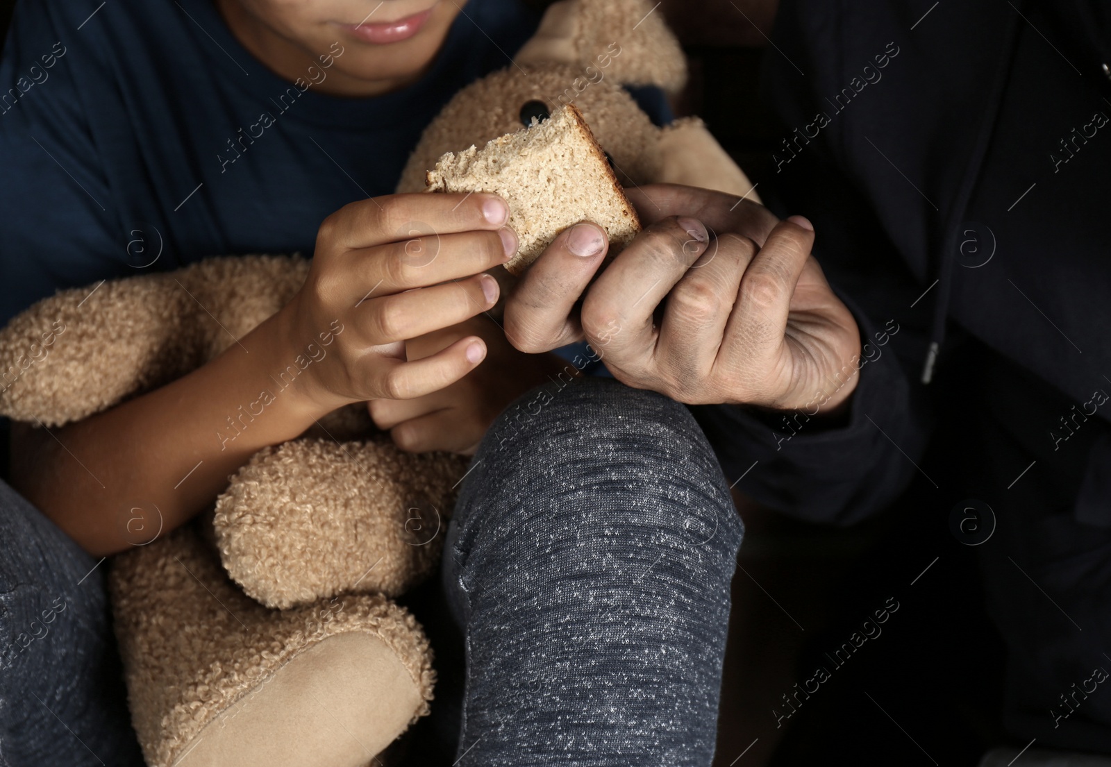 Photo of Poor man giving piece of bread to his son, focus on hands