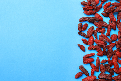 Dried goji berries on light blue background, flat lay. Space for text