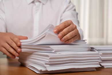 Man stacking documents at table in office, closeup