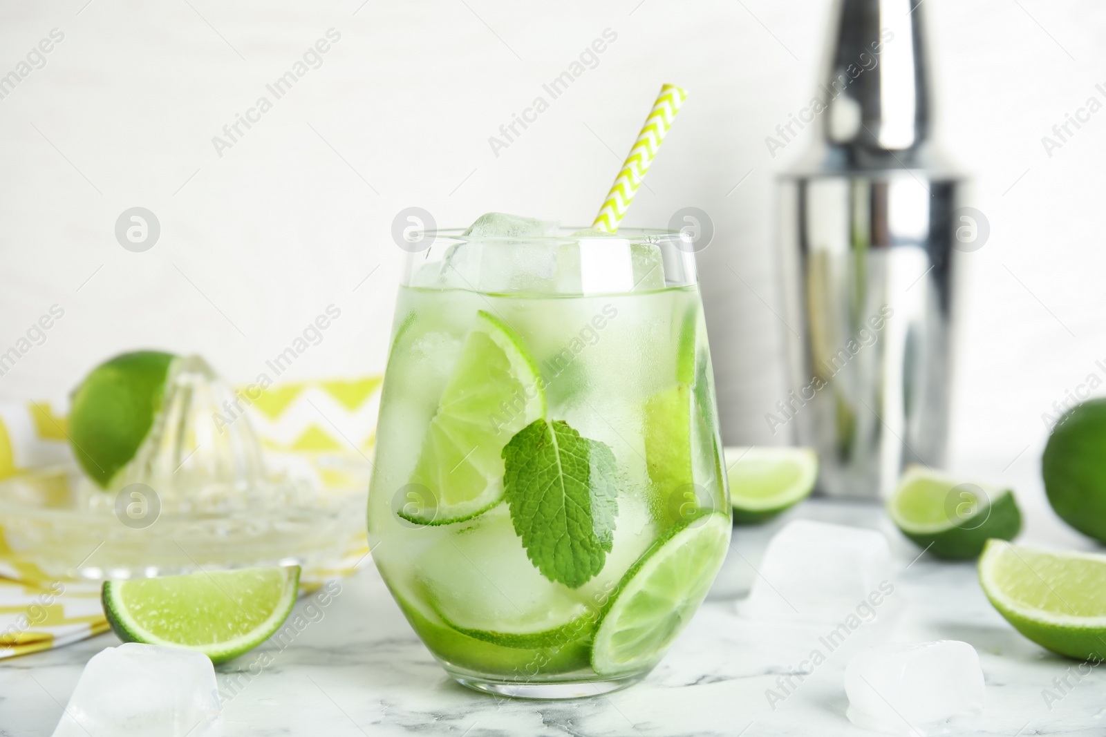 Photo of Delicious mojito and ingredients on white marble table