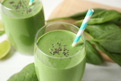 Glasses of healthy green smoothie with fresh spinach on table, closeup